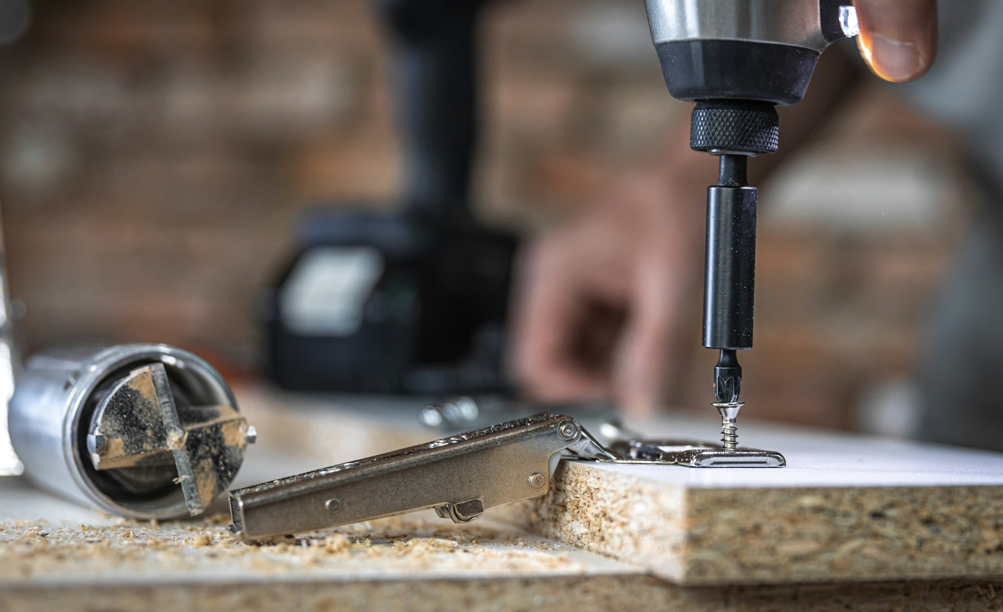 A man is screwing in a screw, a self-tapping screw for wood.